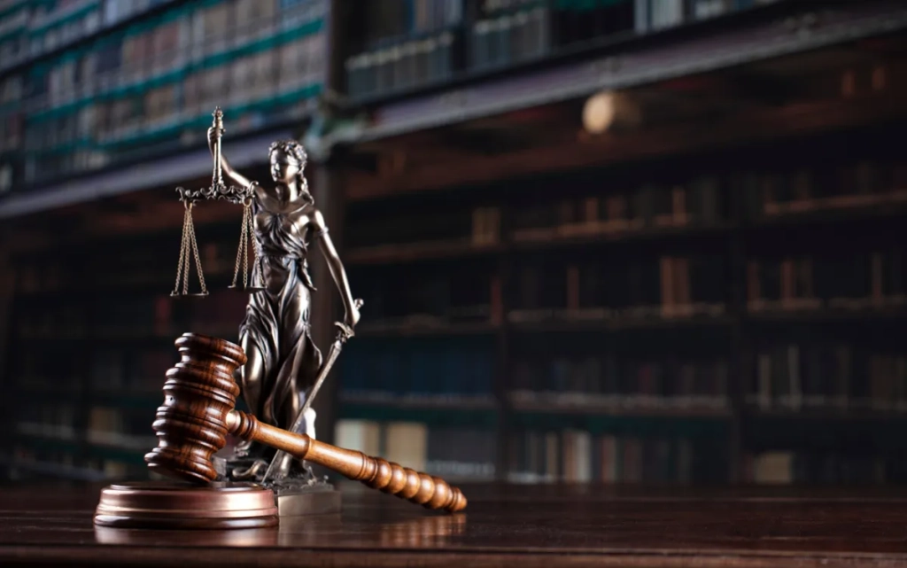 Statue de la justice et marteau de juge sur fond de bibliothèque juridique